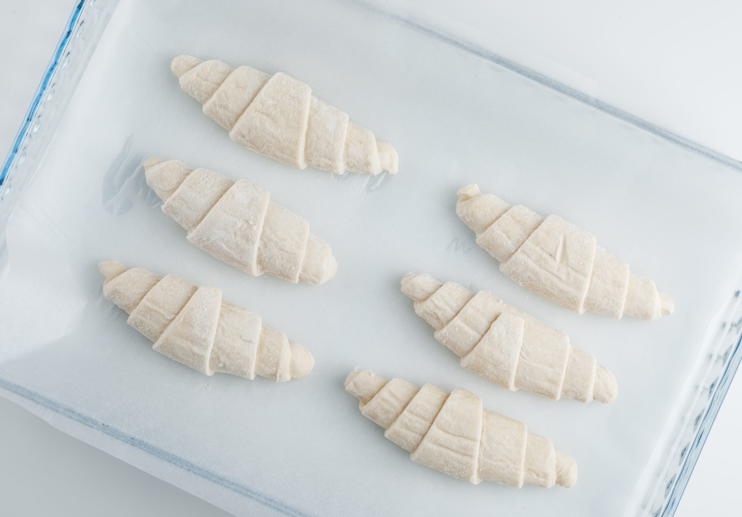 Raw croissant in a plastic bag on white background, flat lay.