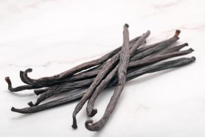 Dried vanilla sticks set up on marble background.