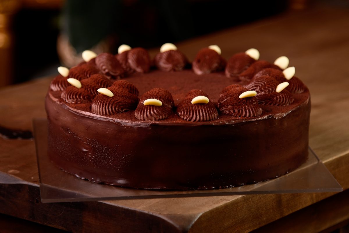 Chocolate cake above with fresh cocoa on wooden table