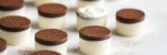 white and brown miniature glasses filled with layered cream with chocolate powder on top