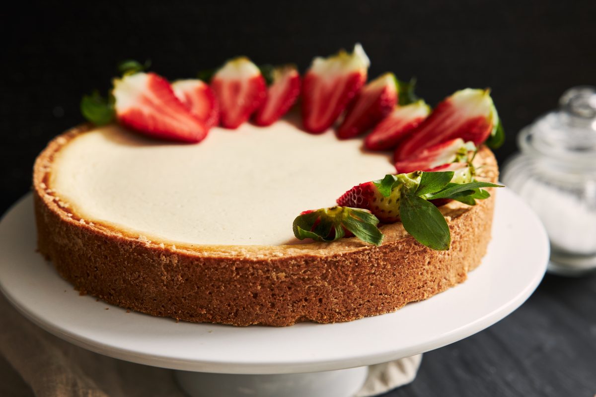 High angle closeup shot of a Strawberry Cheesecake on a white plate and a black background