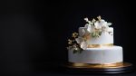 A simple and elegant white wedding cake with gold accents.