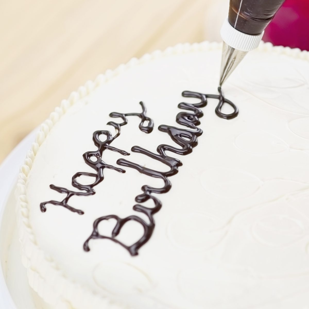 Soft photo of cake decorating using piping tip for writing a wor