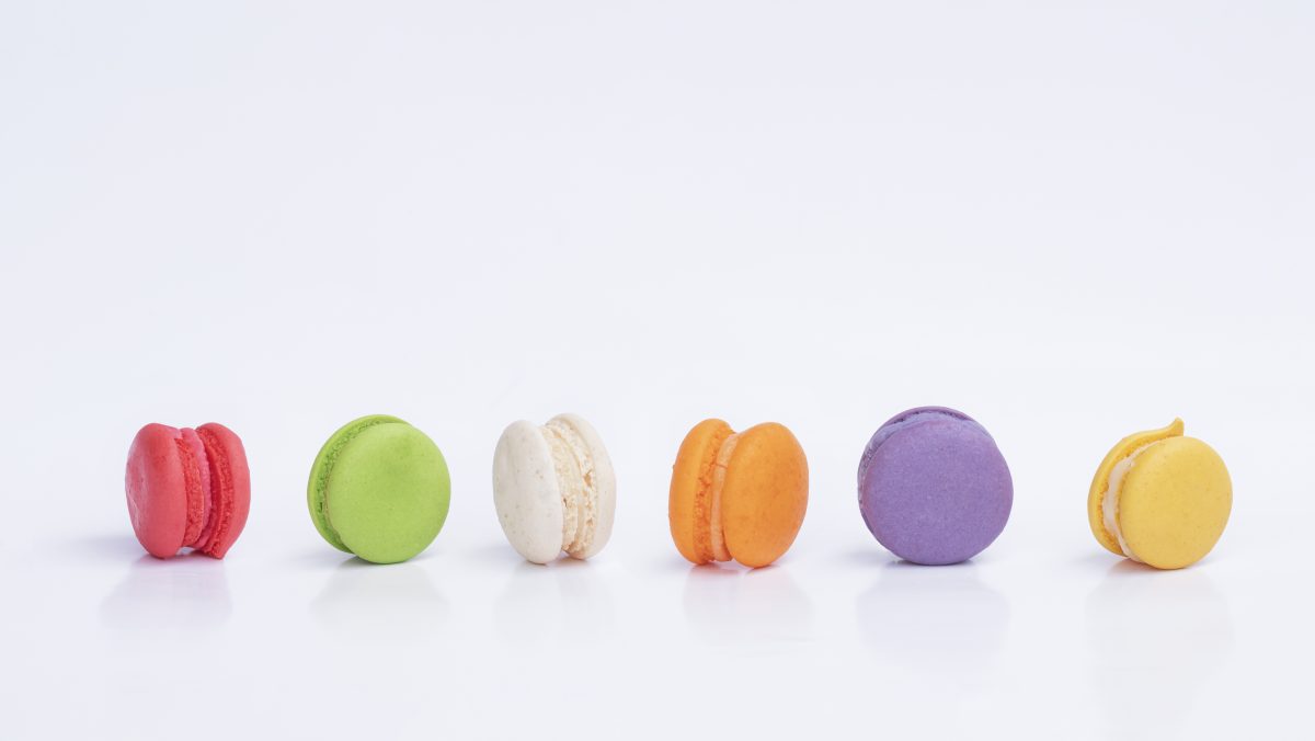 Row of mini colorful macarons on white background