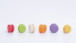 Row of mini colorful macarons on white background