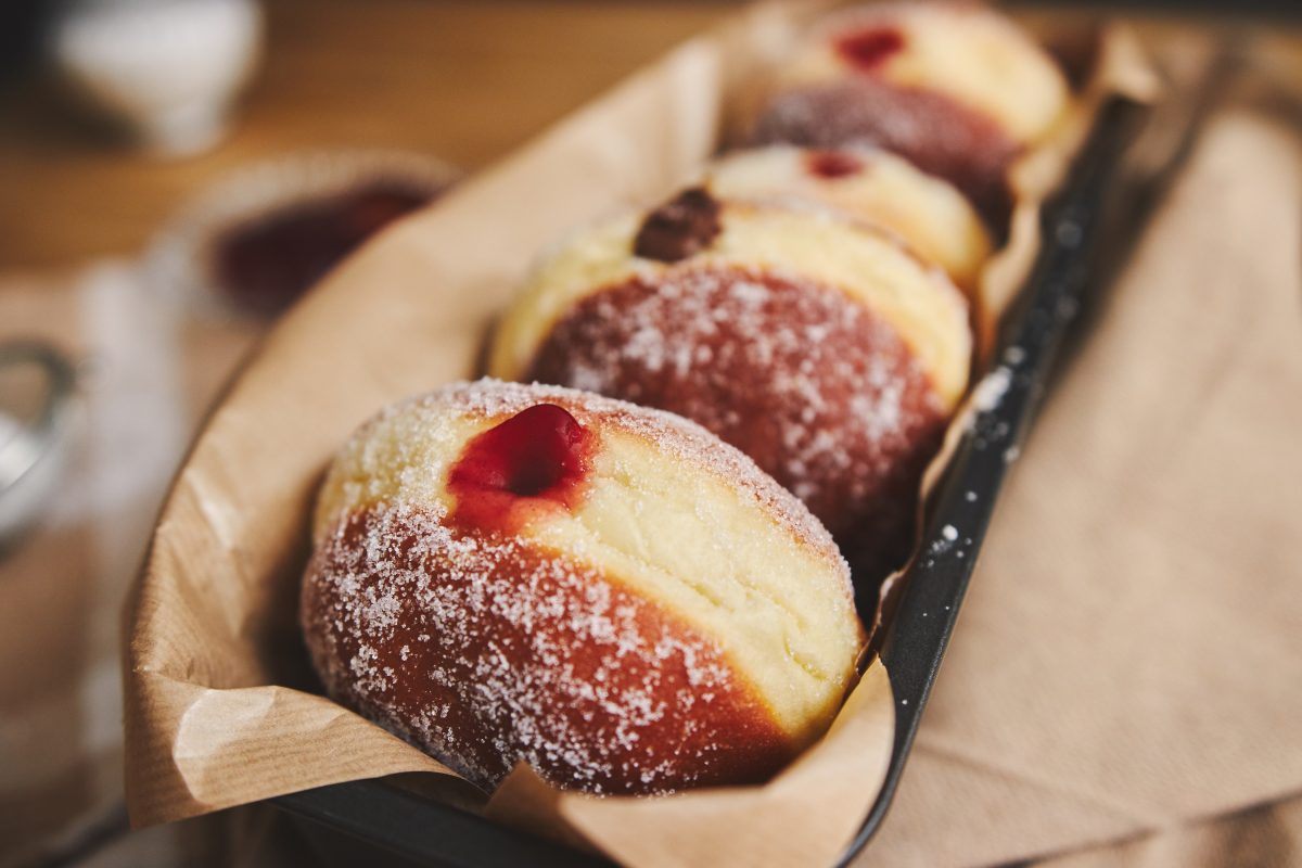Closeup of fluffy doughnuts with jam in a container under the lights with a blurry background