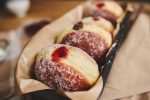 Closeup of fluffy doughnuts with jam in a container under the lights with a blurry background