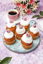Cupcakes decorated whipped cream and frozen raspberries.