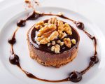 a dessert on a white plate with chocolate and nuts
