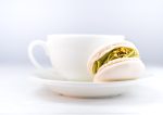 Cup of coffee with macaron on white wooden background. Close up.