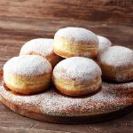 German donuts with jam and icing sugar. Carnival powdered sugar raised donuts.