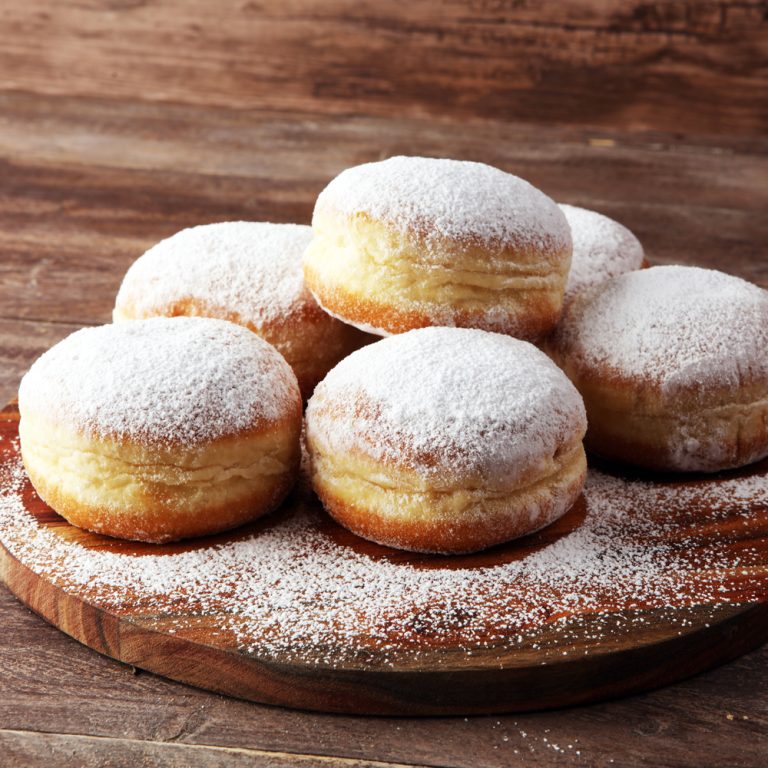 German donuts with jam and icing sugar. Carnival powdered sugar raised donuts.